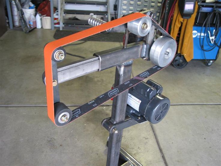 an orange and black object sitting on top of a tripod in a room filled with tools