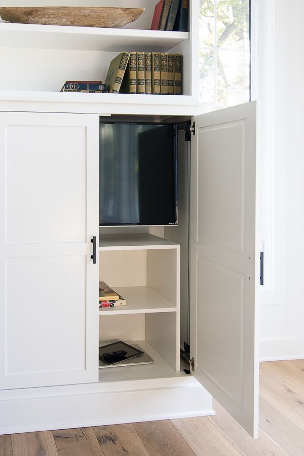 an open cabinet with books and a television in it