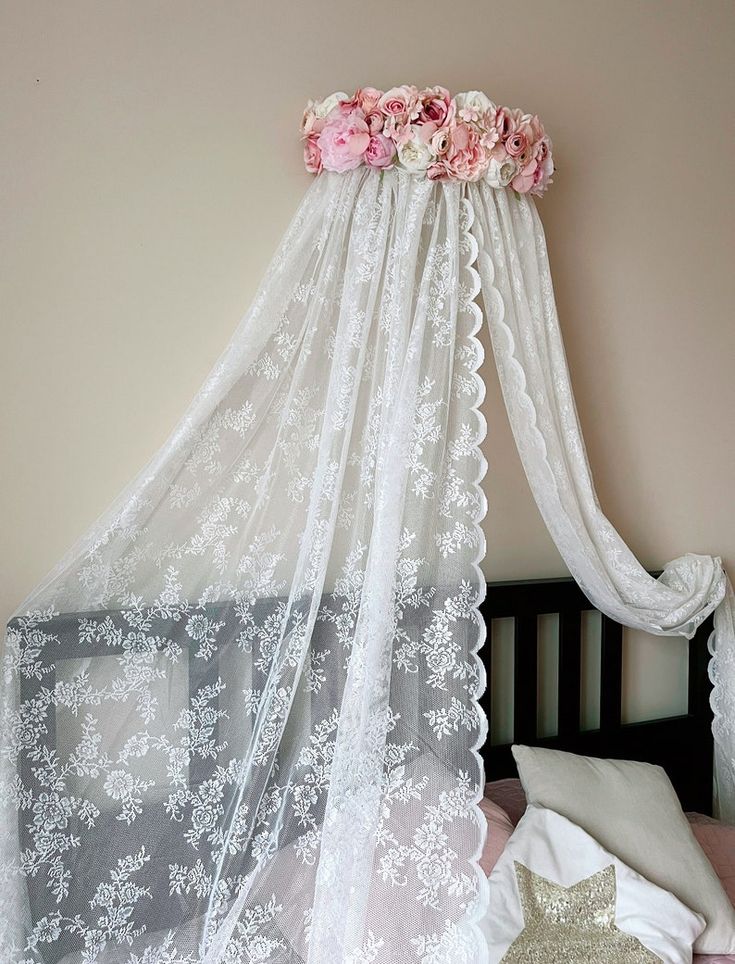 a canopy bed with white lace and pink flowers