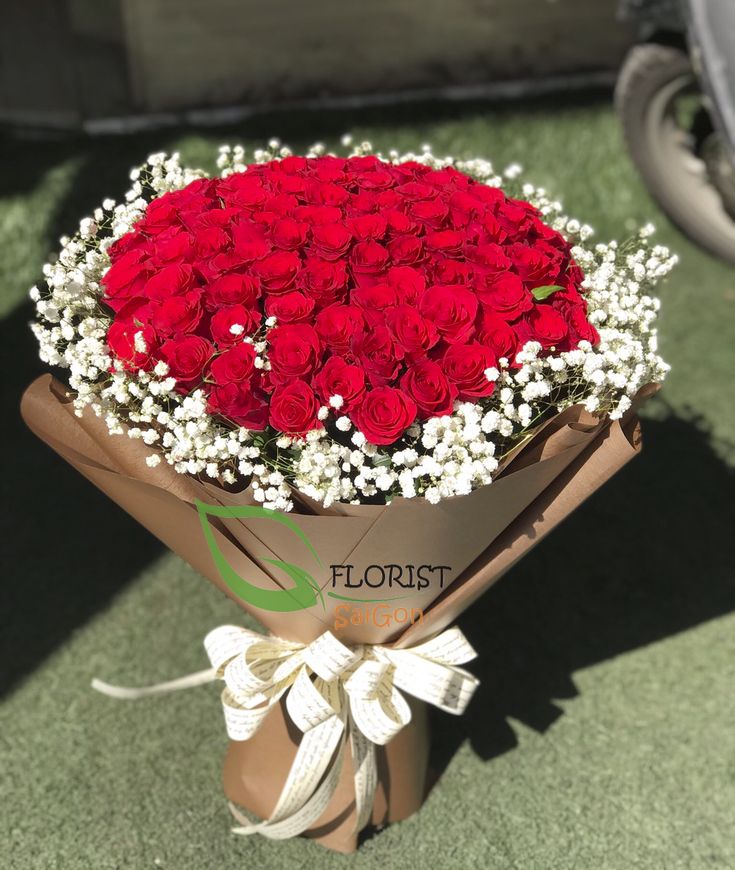 a bouquet of red roses is wrapped in brown paper and tied with a white ribbon