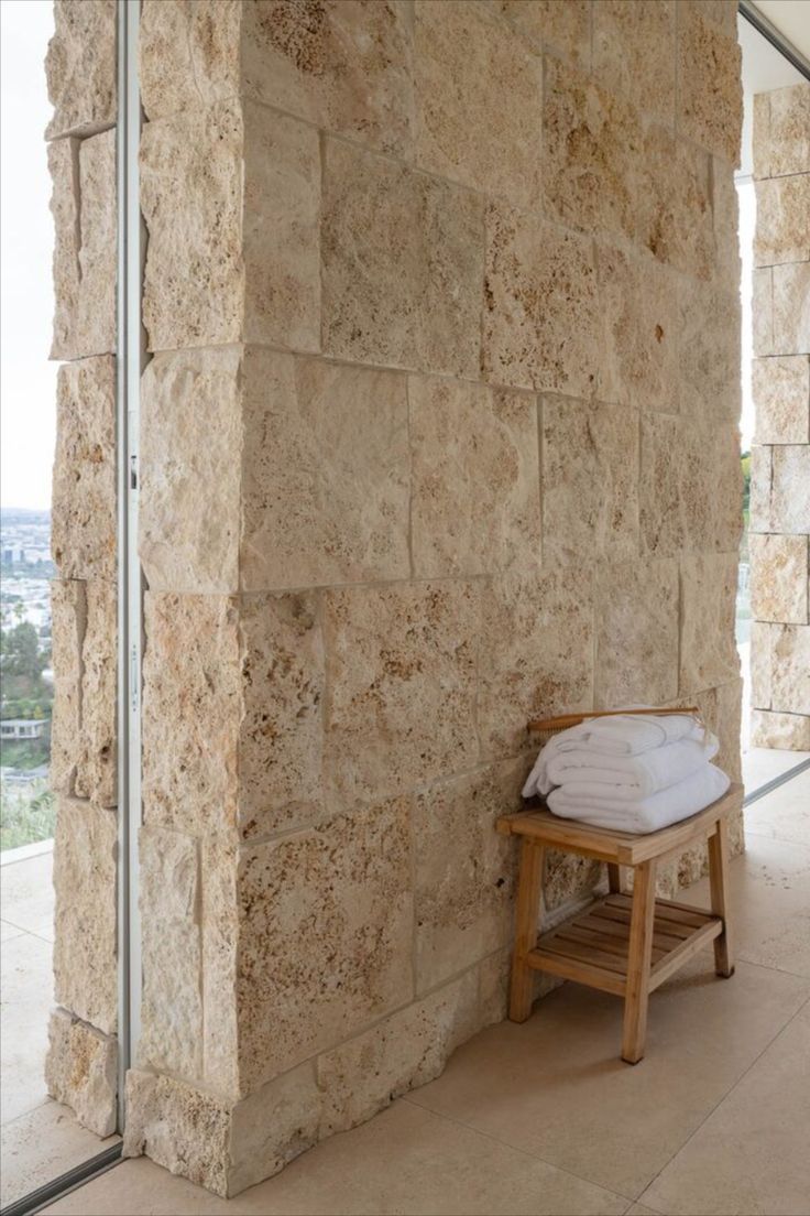 a bathroom with stone walls and wooden stool