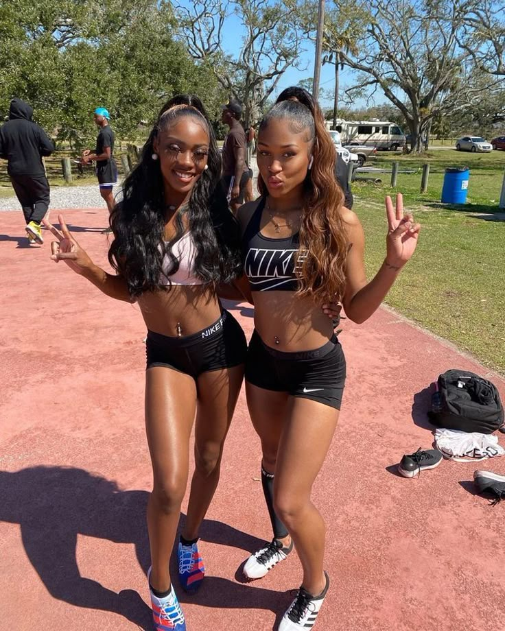 two young women standing next to each other on a tennis court in shorts and sports bras