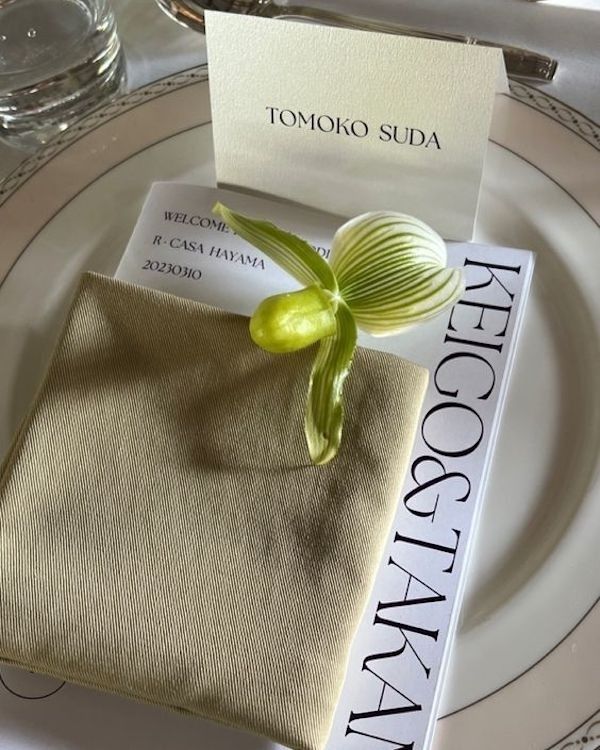 a place setting with napkins and an orchid on it, along with a business card