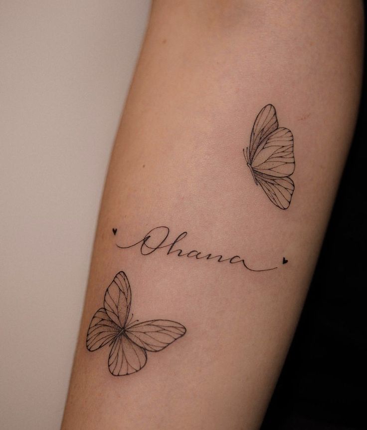 two butterflies with the word mama tattooed on their arm and behind them is a name