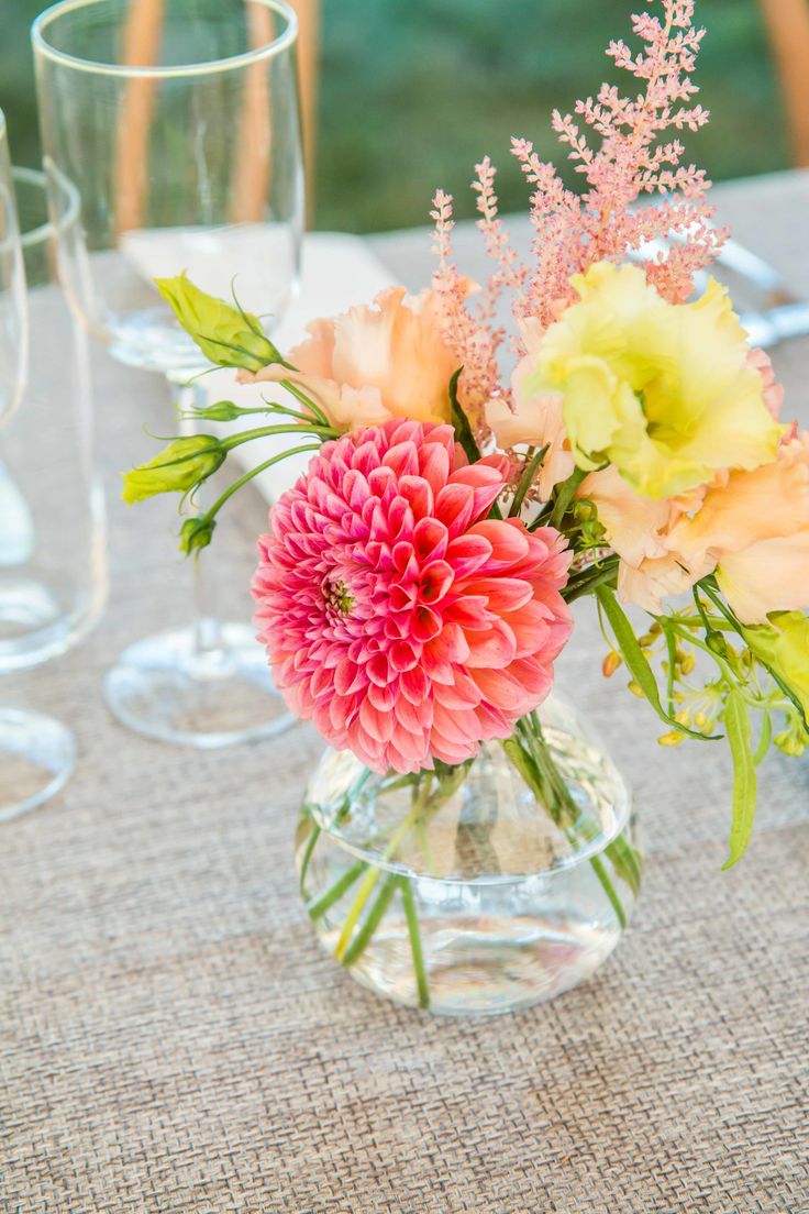 a vase filled with flowers sitting on top of a table next to empty wine glasses