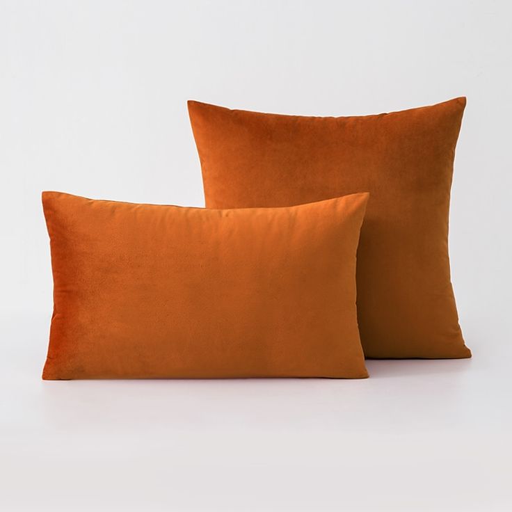 two orange pillows sitting next to each other