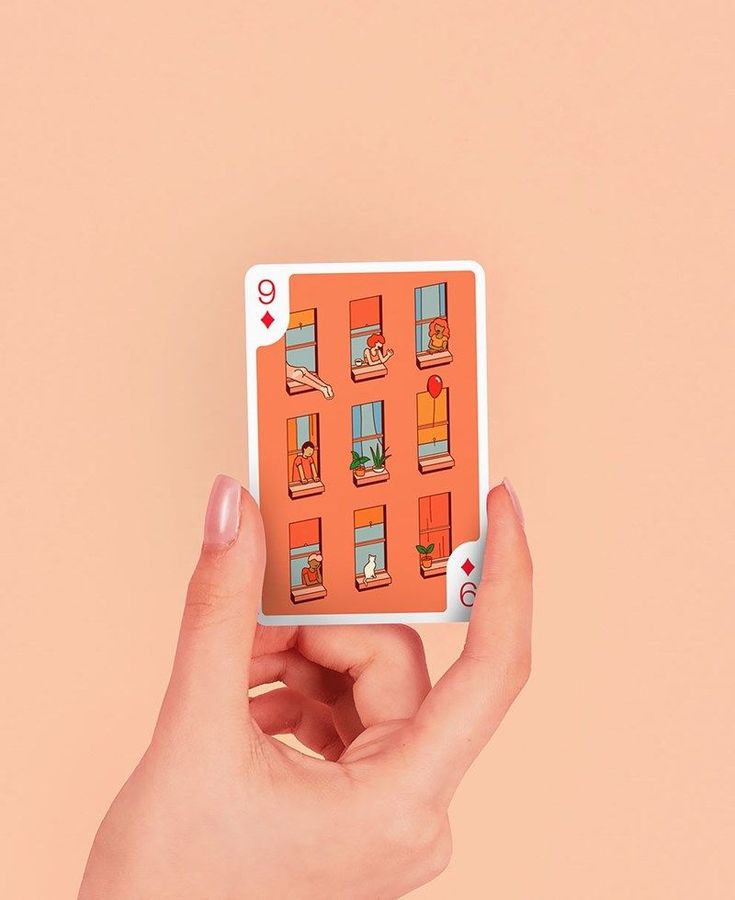 a person's hand holding up an orange card with pictures of windows on it