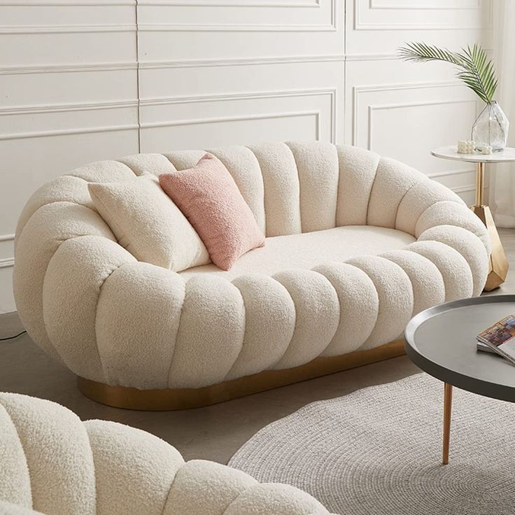 a living room filled with furniture and a round coffee table in front of a white wall