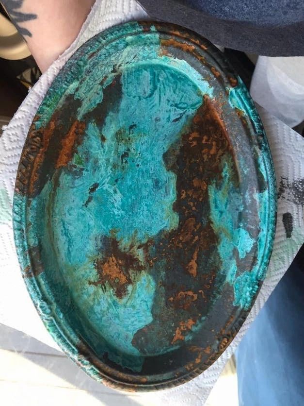 an old rusty plate is being held in someone's hand