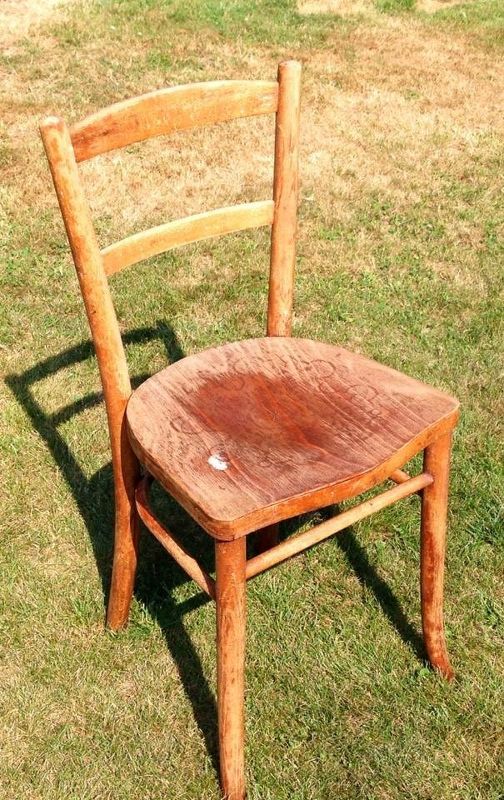 a wooden chair sitting on top of a grass covered field