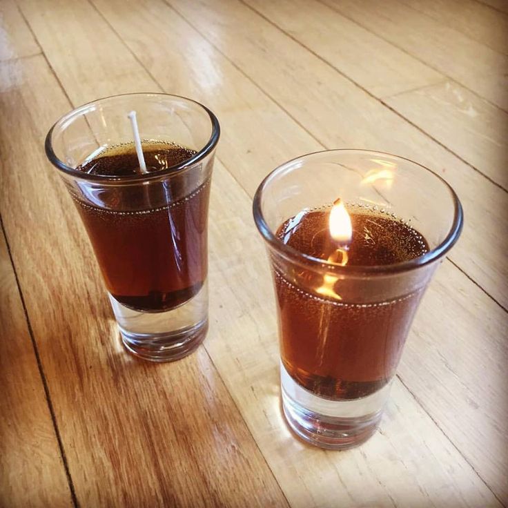 two glasses filled with liquid sitting on top of a wooden table next to each other