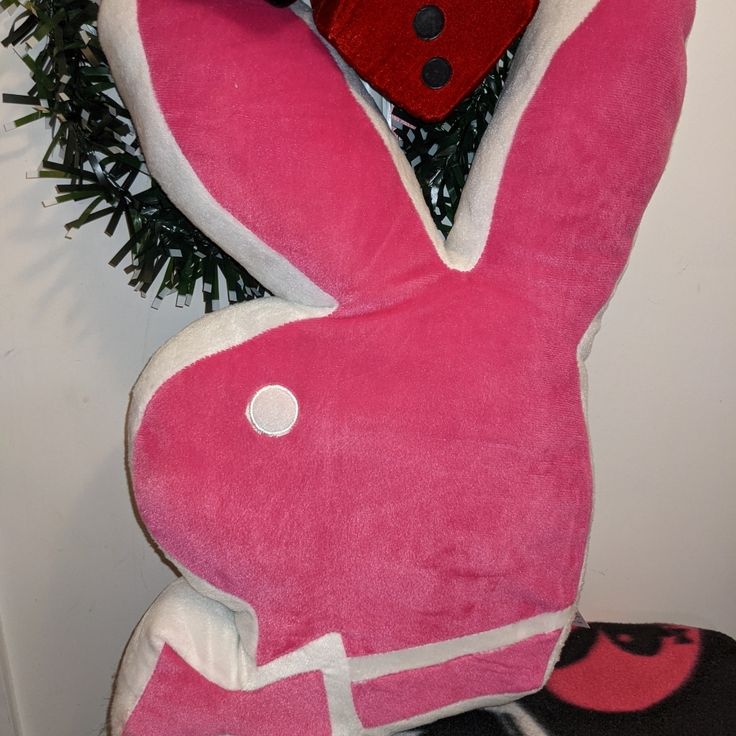 a pink stuffed rabbit sitting next to a christmas tree