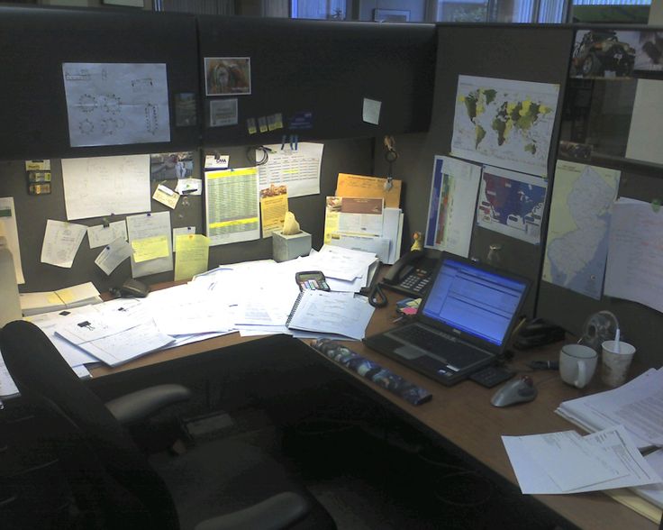 an office cubicle is cluttered with papers and paperwork