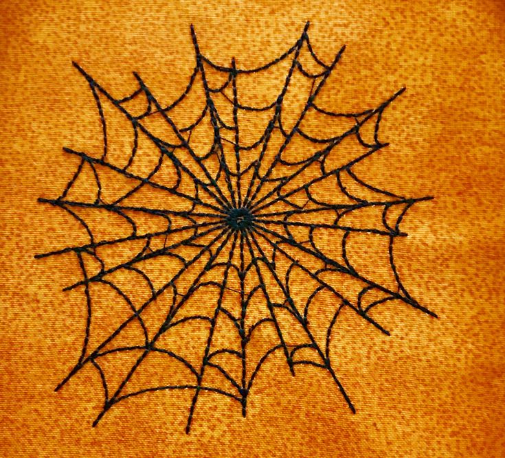 a spider web is shown in the middle of an orange background with black thread on it