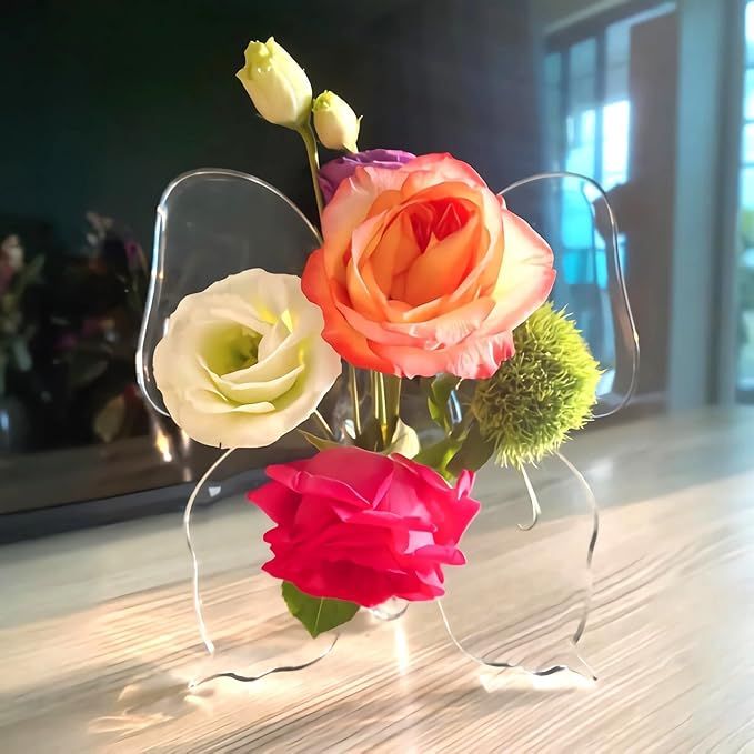 three different colored flowers in a clear vase