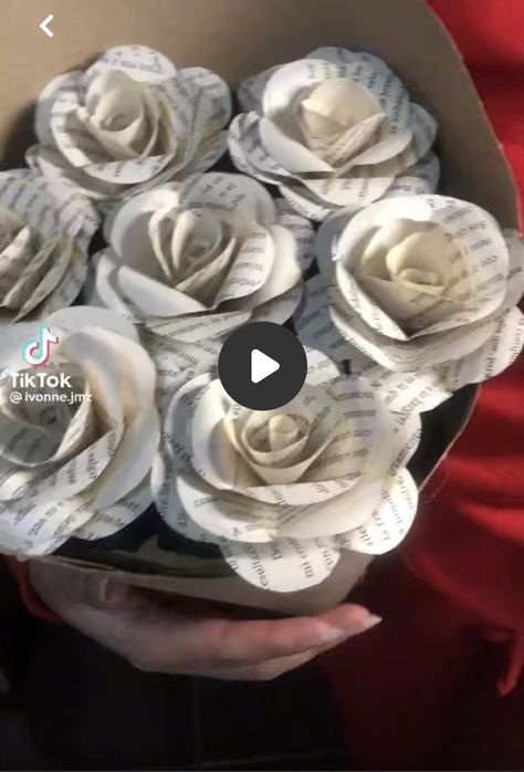 a person holding a bouquet of paper roses in front of a box with sheet music on it