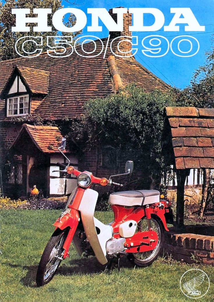 a red and white moped parked on top of a lush green field next to a house