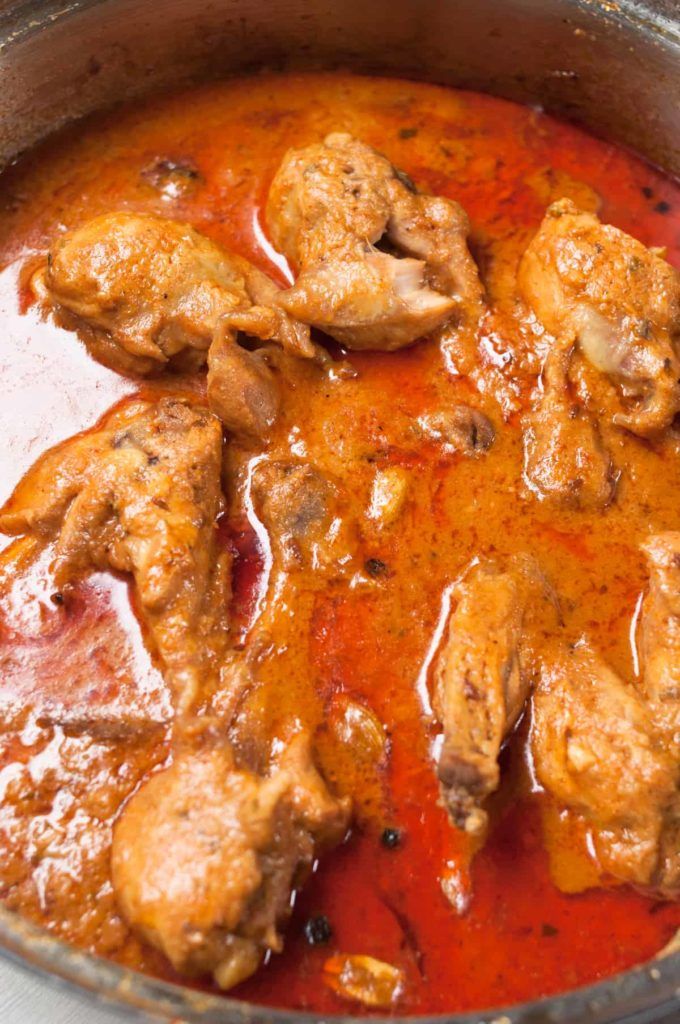 some meat is cooking in a pot with red sauce on the side and it looks delicious