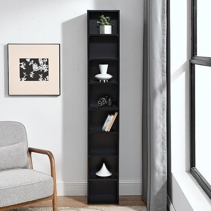 a black book shelf in the corner of a room with a chair and pictures on the wall