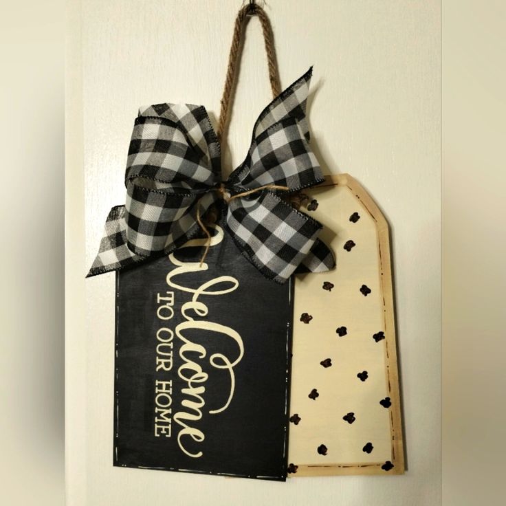 the door hanger is decorated with black and white plaid ribbon, which says welcome to our home