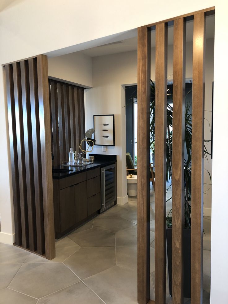 an open door leading to a kitchen and living room with wood slats on the walls