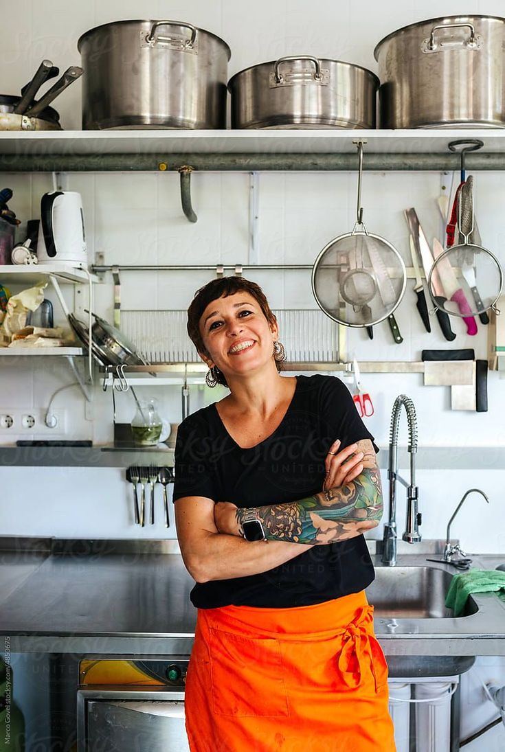 a woman in an orange apron is smiling at the camera