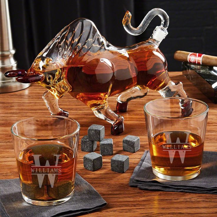 two shot glasses with whiskey in them and a glass bull figurine on the table