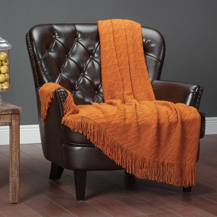 an orange blanket draped over a black chair