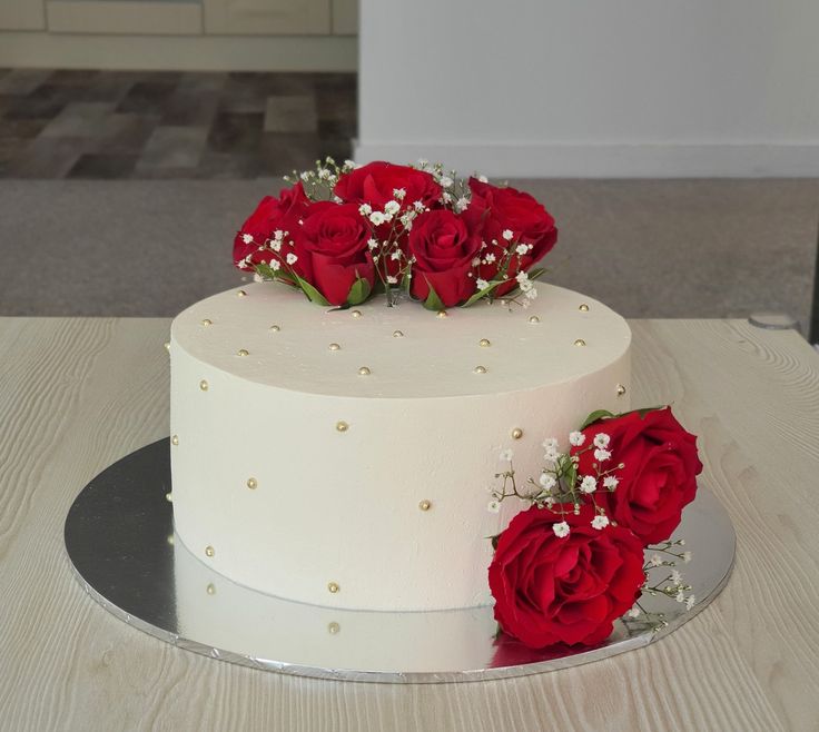 a white cake with red roses on top