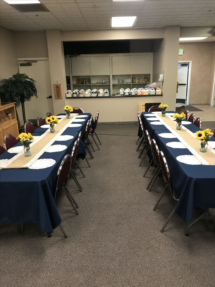 a long table is set up with blue cloths and sunflowers in vases