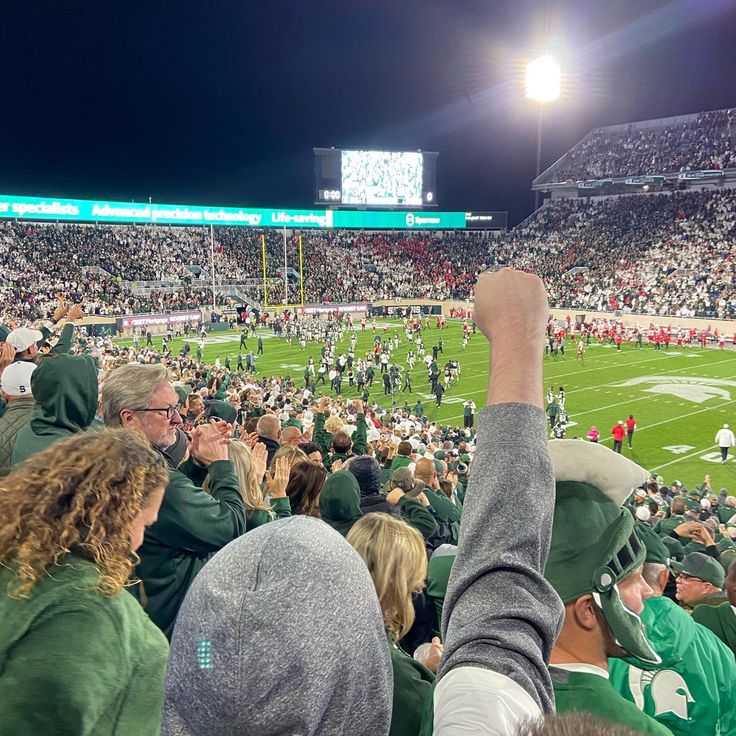 a football stadium filled with people and fans watching the game from the stands at night