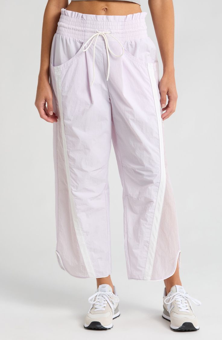 Traditionally sporty track attire gets a street-style reset in these water-resistant nylon pants refreshed with an ultrawide smocked waistband and wavy cropped hems. 25 1/2" inseam; 18" leg opening; 14" front rise; 18" back rise (size Medium) Smocked/drawstring waist Front scoop pockets; back patch pockets Water resistant 100% nylon Machine wash, tumble dry Imported Pink Parachute Pants For Spring Loungewear, Spring Pink Parachute Pants For Loungewear, Spring Sportswear Parachute Pants With Relaxed Fit, Spring Sportswear Pants With Elastic Waistband, Relaxed Fit Parachute Pants For Spring Sportswear, Spring Sportswear Parachute Pants, Summer Athleisure Parachute Pants With Elastic Waistband, Spring Activewear With Elastic Side Panels, Sporty Summer Parachute Pants With Loosely Fitted Hips