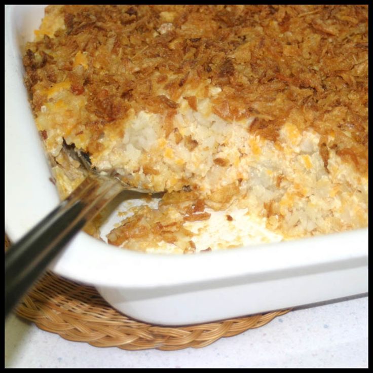 a close up of a casserole in a white dish with a serving utensil