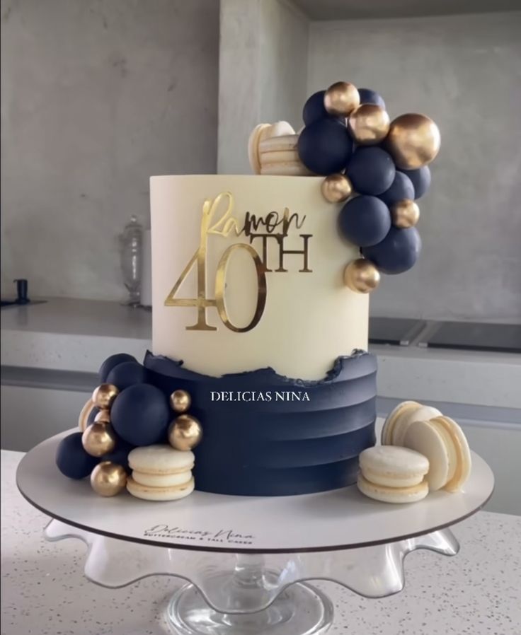 a blue and white cake with gold decorations on top is sitting on a table in front of a window