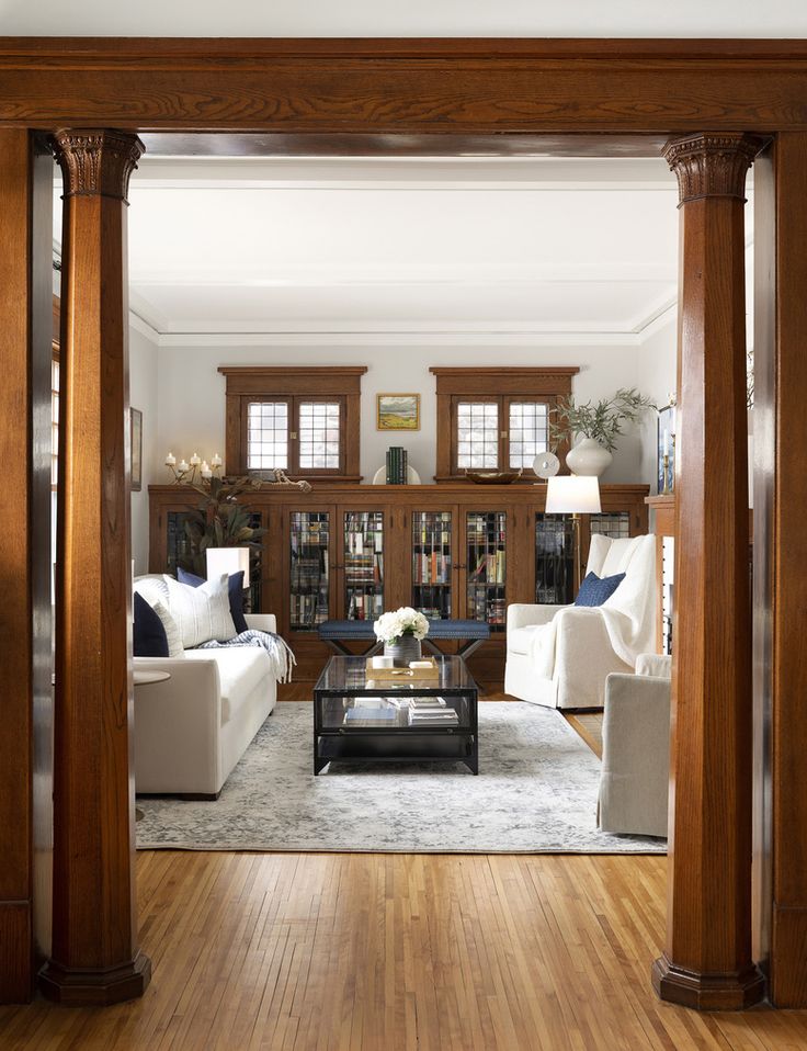 a living room filled with white furniture and wooden pillars in the middle of it's floor