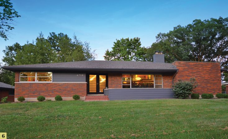 a brick house sits in the middle of a grassy field