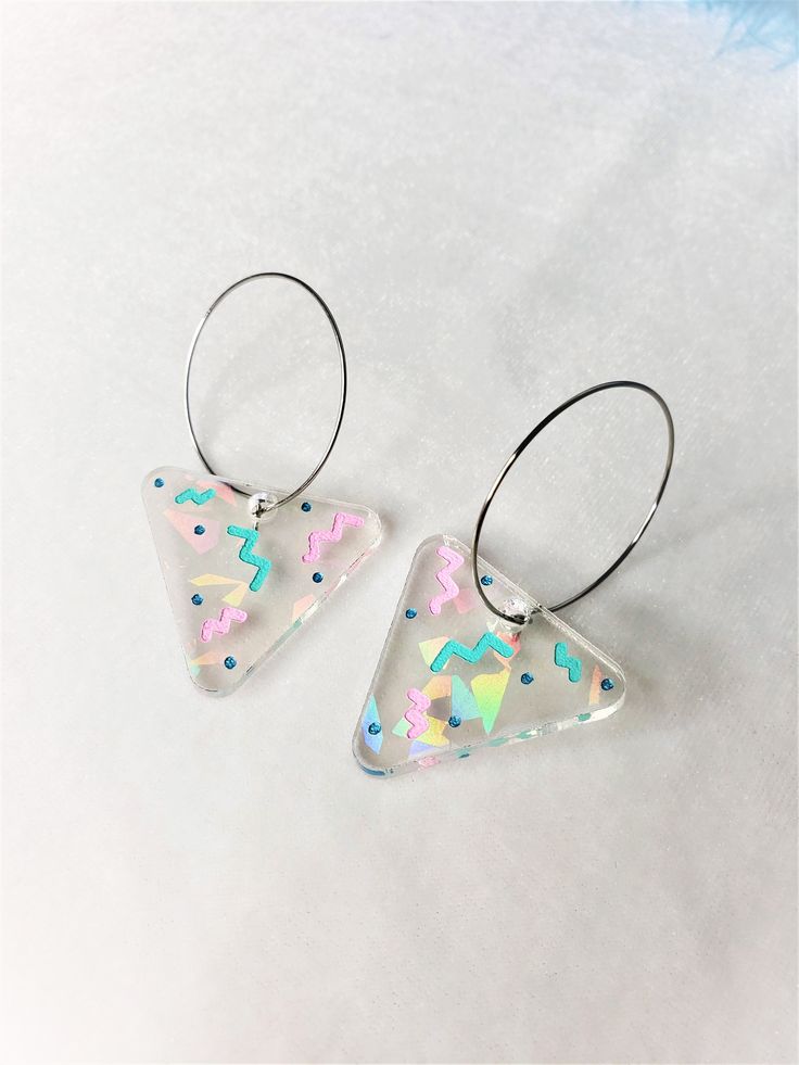 Rainbow Triangle 80s Holiday Party Hoop Earrings The hoops are made of stainless steel, they are about 1.25 inches acrossApproximately 1.25" wide, and 2.25" long from top of metal hoopThese are super fun and colorful earrings. Bright and cheery! With the lovely pastels and retro vibes, these earrings should give a good mood booster. They are made with a clear acrylic that feature rainbow iridescent shards of glitter, that shines differently depending on the light. The engraved details are hand p Trendy Colorful Party Hoop Earrings, Colorful Trendy Hoop Earrings For Gift, Trendy Rainbow Hoop Earrings, Colorful Trendy Hoop Earrings As Gift, Trendy Colorful Hoop Earrings For Party, Colorful Small Hoop Trendy Earrings, Trendy Colorful Hoop Earrings For Gifts, Trendy Colorful Hoop Earrings As Gift, Trendy Small Hoop Colorful Earrings