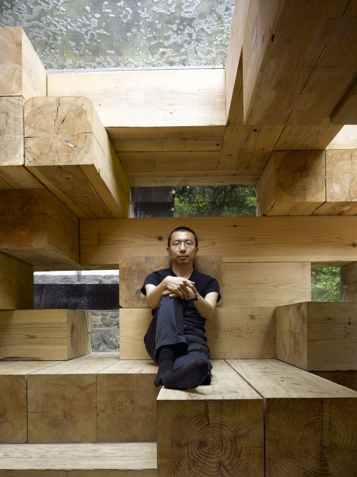 a man sitting on top of a wooden bench in a room filled with wood planks