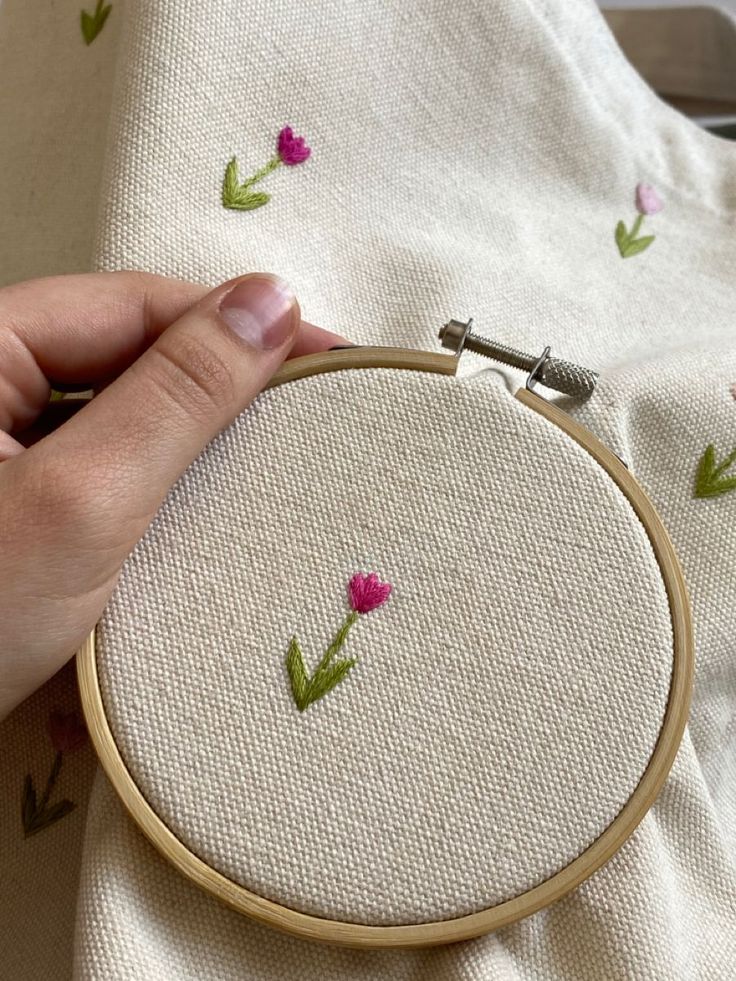 someone is stitching flowers on the fabric with a sewing needle in their left hand