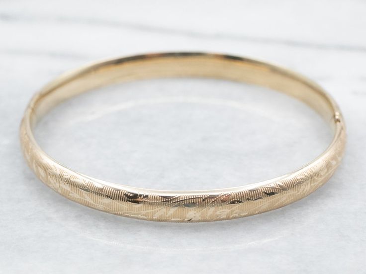 "The details on this vintage 14-karat gold bangle are simply stunning!  Intricate scrolling botanical designs are engraved in warm yellow gold, covering the entire bracelet. Beautiful on its own or layered with other bracelets this piece is perfect for day or evening wear. Metal: 14K Yellow Gold Width: 6.3 mm Inside Circumference: 6 1/2 Inches Marks: \"JW 14K\" Stamped on the inside band To view a video of this piece check out the link below: https://vimeo.com/831970277 SKU #: A26074 Each piece Bangle Stacking, Yellow Gold Bangle, Warm Yellow, Gold Bangle Bracelet, Gold Bangle, Hinged Bangle, Vintage Botanical, Bracelet Stack, Gold Bangles