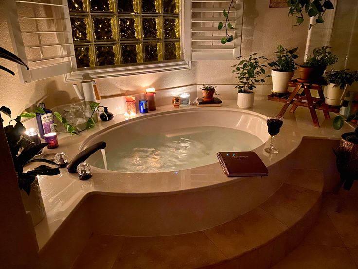 a bathroom with a large jacuzzi tub next to a window and potted plants