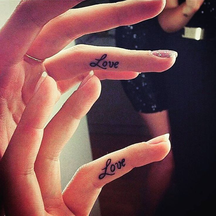 two fingers with the word love tattooed on them