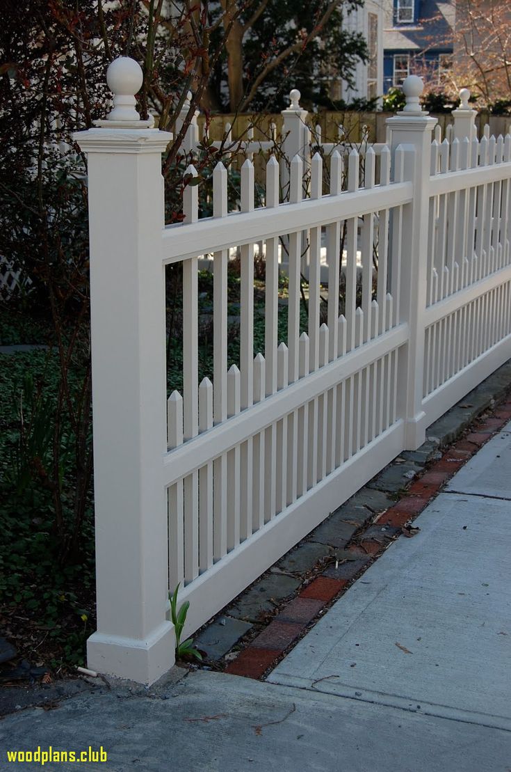 a white picket fence next to a sidewalk