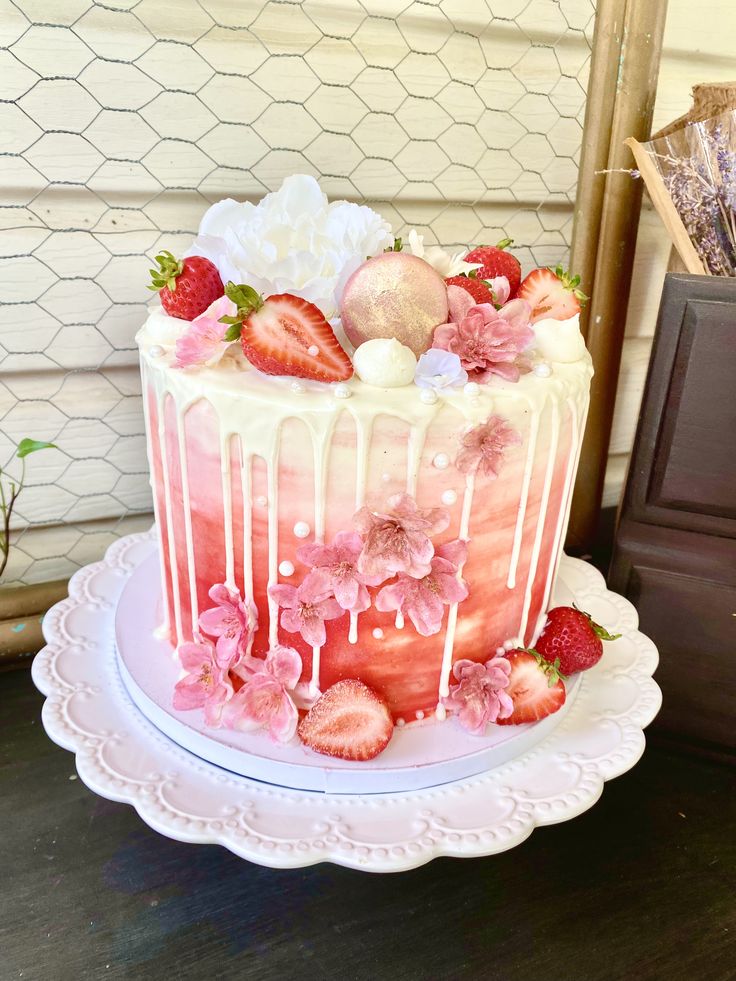 a strawberry cake with white icing and fresh strawberries on top