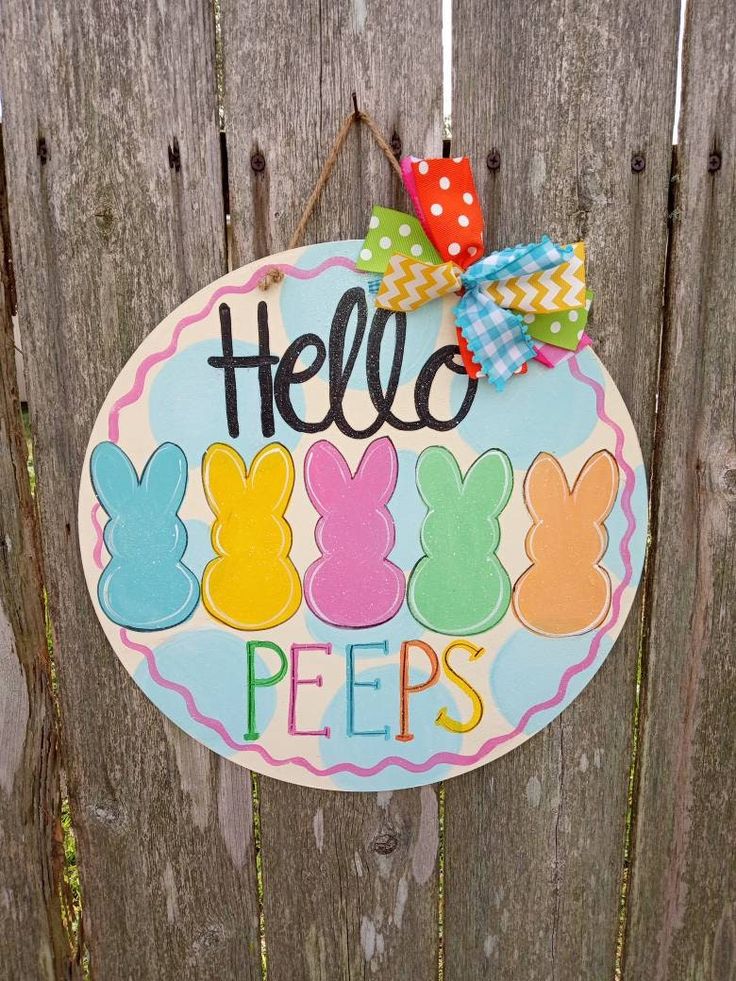 a sign that says hello pees hanging on the side of a wooden fence with bunnies