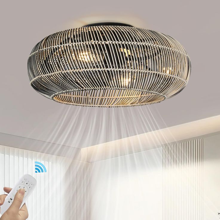 a person holding a remote control under a light fixture in a room with white walls