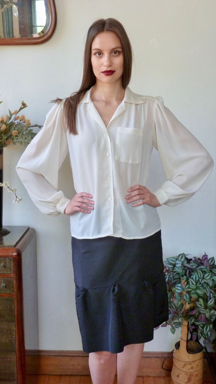 "Beautiful classic detailed vintage blouse by Jack Mulqueen. Vintage is 1980s or 1990s. Voluminous full sleeves, finely gathered at shoulders, and at the 1 1/2\" cuffs. Tiny mother of pearl buttons at cuffs. Yoked shoulders and back. Gathered at front yoke. Single patch pocket with eight rows of top stitching detail. White V neck notched collar with five rows of top-stitching. Top stitching down the front with four tiny mother of pearl buttons. Semi sheer ivory polyester crepe fabric. Labelled: Classic Spring Tops With Bishop Sleeves, Classic Balloon Sleeve Tops For Spring, Formal Long Sleeve Blouse With Gathered Sleeves, Classic Bishop Sleeve Office Blouse, Fitted Button-up Blouse With Gathered Sleeves, Classic Office Blouse With Bishop Sleeves, Classic Bishop Sleeve Blouse For Office, Classic Blouse With Balloon Sleeves And Button Cuffs, Classic Balloon Sleeve Blouse For Fall