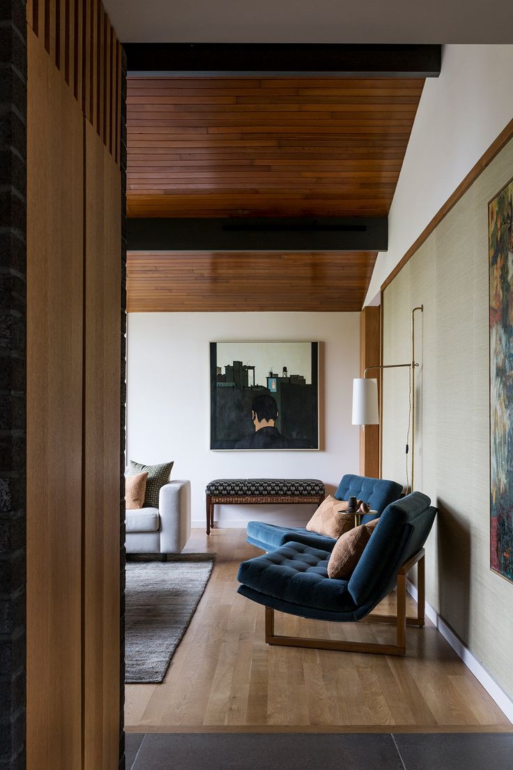 a living room with wood paneling and couches on the floor in front of a painting