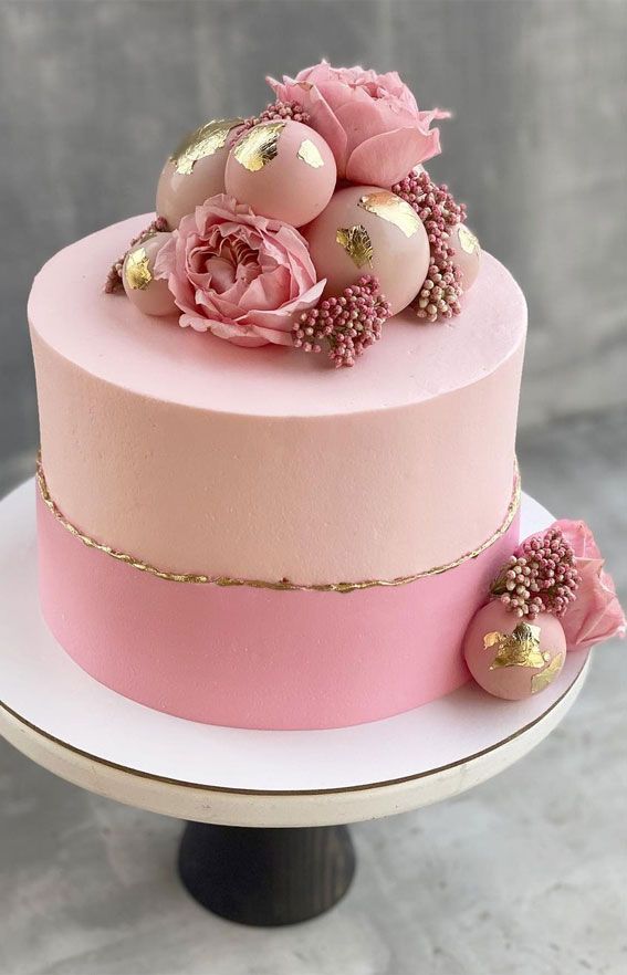 a pink and gold cake with flowers on top