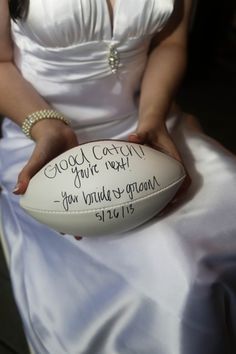 a woman in a white dress holding a football with writing on the inside of it